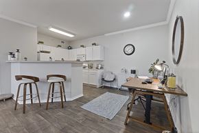 Denton apartment for rent - A kitchen with white cabinets and a bar area with stools.