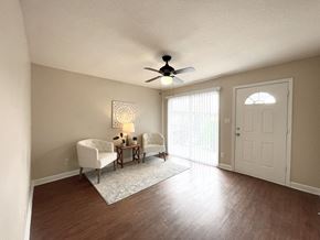 Houston apartment for rent - an empty living room with a ceiling fan and a door to a balcony
