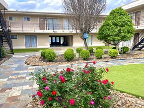 Houston apartment for rent - a building with a courtyard and flowers in front of it