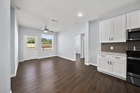 Houston apartment for rent - an empty kitchen and living room with white cabinets and a ceiling fan