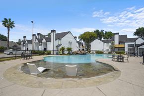 Houston apartment for rent - A pool surrounded by a stone patio and chairs.