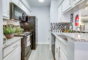 Houston apartment for rent - A kitchen with a black refrigerator and white cabinets.