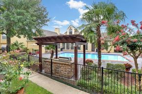 Houston apartment for rent - A pool area with a black fence and a gazebo.