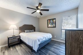 Fort Worth apartment for rent - A bedroom with a bed, nightstand, and a ceiling fan.