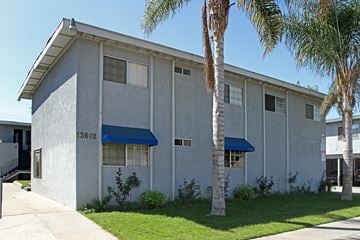 Santa Ana apartment for rent - A building with a blue awning and palm trees in front.