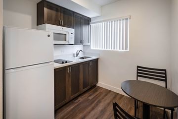 Stanton apartment for rent - A kitchen with a white refrigerator, brown cabinets, and a black chair.
