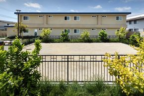 Stanton apartment for rent - A building with a black fence and green bushes in front.