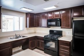 Riverside apartment for rent - A kitchen with dark brown cabinets and black appliances.