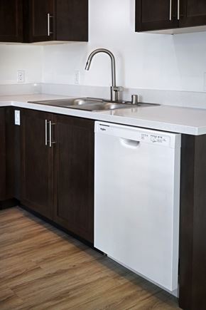 San Juan Capistrano apartment for rent - A white dishwasher is in a kitchen with dark brown cabinets.