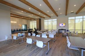 Fontana apartment for rent - A conference room with a long table and chairs, a television on the wall, and a view of the outdoors through the windows.