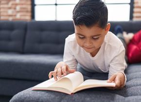 Fontana apartment for rent - A young boy is reading a book on a grey couch.