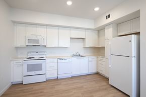 Santa Ana apartment for rent - A white kitchen with a refrigerator on the right.