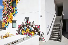 Santa Ana apartment for rent - A white building with a staircase and a mural on the wall.