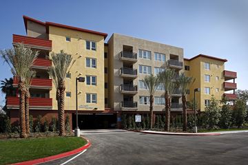 Irvine apartment for rent - A large apartment complex with a red roof and palm trees in front.
