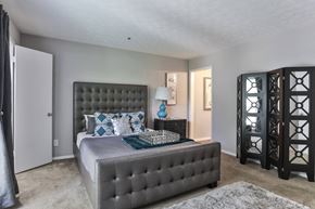 Stone Mountain apartment for rent - A bedroom with a large bed and a grey tufted headboard.