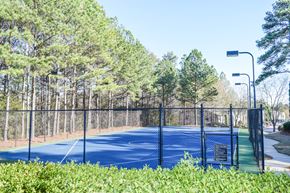 College Park apartment for rent - A tennis court surrounded by a fence and trees.