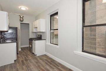 Bronx apartment for rent - A kitchen with white appliances and wooden floors.