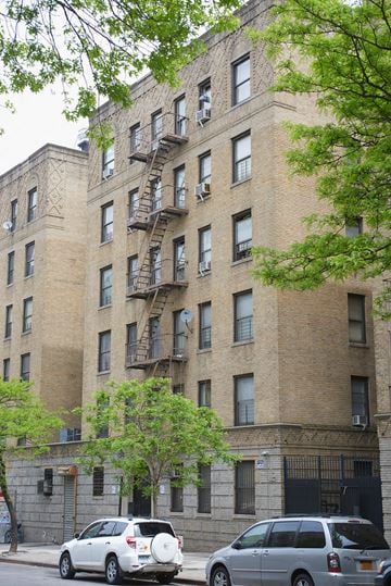 Bronx apartment for rent - A tall brick building with a fire escape on the side.