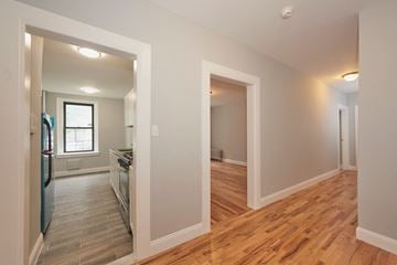 Bronx apartment for rent - A kitchen with a refrigerator, sink, and oven is visible through an open door.