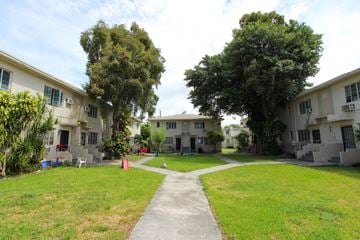 Miami apartment for rent - A grassy area with a concrete walkway separates two rows of houses.