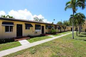 Miami apartment for rent - a row of yellow houses with palm trees in the background