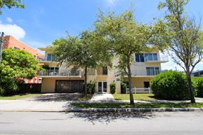 Miami apartment for rent - a large yellow and white apartment complex with trees in front of it