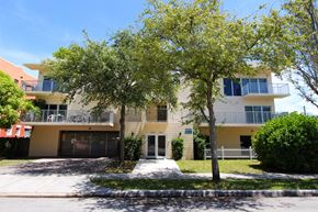 Miami apartment for rent - a large yellow and white apartment building with two trees in front of it