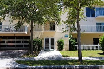 Miami apartment for rent - A building with a white fence and a tree in front of it.