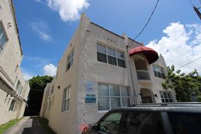 Miami apartment for rent - a white building with an awning and a car parked in front of it
