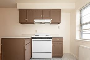 Trenton apartment for rent - A white dishwasher is in a kitchen with brown cabinets.