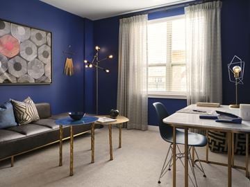 Worcester apartment for rent - A blue living room with a grey couch, a blue coffee table, a black chair, and a painting on the wall.