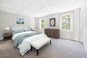 Shirley apartment for rent - A bedroom with a large bed, a window and carpet flooring at Birchwood Townhomes in Shirley, MA.