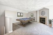 Shirley apartment for rent - A loft space with pool table in a room with a fireplace and a clock on the wall with carpet floor at Birchwood Hills Townhomes in Shirley, MA.