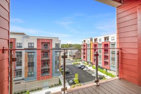 North Attleboro apartment for rent - A view from a balcony of a parking lot and apartment buildings.