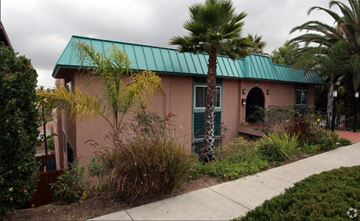 San Diego apartment for rent - A house with a green roof and a palm tree in front.