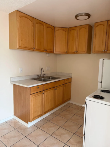 National City apartment for rent - A kitchen with wooden cabinets and a white dishwasher.