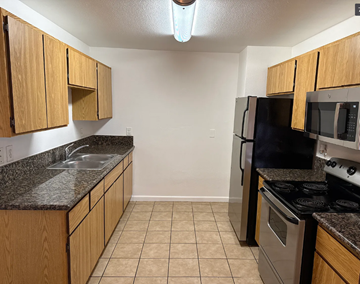 San Diego apartment for rent - A kitchen with wooden cabinets and black countertops.