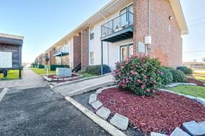 Harvey apartment for rent - A red brick building with a balcony and a flower bed in front.