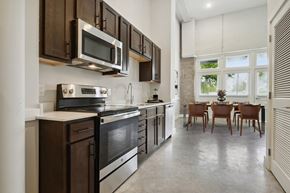 Donaldsonville apartment for rent - a kitchen with wooden cabinets and stainless steel appliances and a dining room with a window