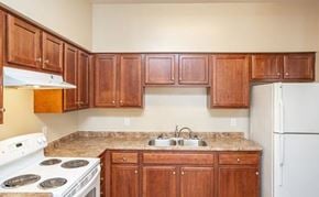 Houma apartment for rent - A kitchen with wooden cabinets and a white stove top oven.