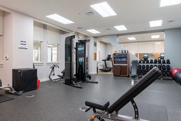 Richmond apartment for rent - A gym with a variety of equipment including a treadmill, weights, and a bench press.