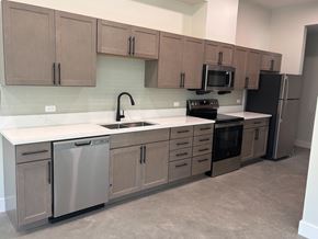New Orleans apartment for rent - A kitchen with brown cabinets and a black fridge.