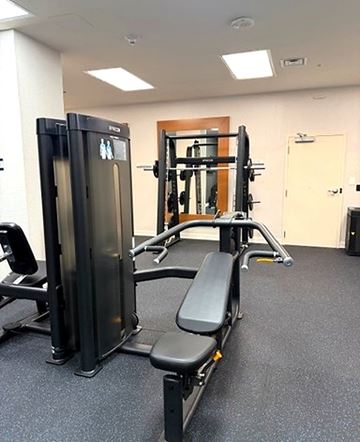 Richmond apartment for rent - A gym with a squat rack, a bench, and a barbell.