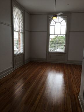 New Orleans apartment for rent - A room with wooden floors and a large window with blinds.