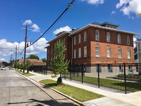 New Orleans apartment for rent - A red brick building with a black fence in front.