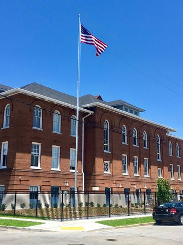 New Orleans apartment for rent - A red brick building with an American flag on top.