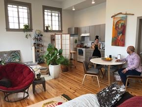 New Orleans apartment for rent - A man is sitting at a table in a room with a woman standing in the kitchen.