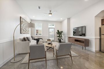 Lake Charles apartment for rent - A modern living room with a grey sofa, a wooden floor, and a television on the wall.