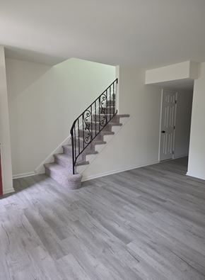 Dover townhouse for rent - A staircase with a metal railing and a grey stone wall.