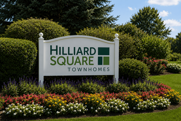 Hilliard townhouse for rent - A sign for Hilliard Square Townhomes is surrounded by flowers and greenery.